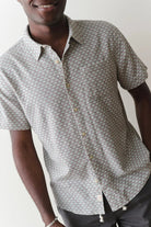 Man wearing a patterned short-sleeve shirt against a plain background