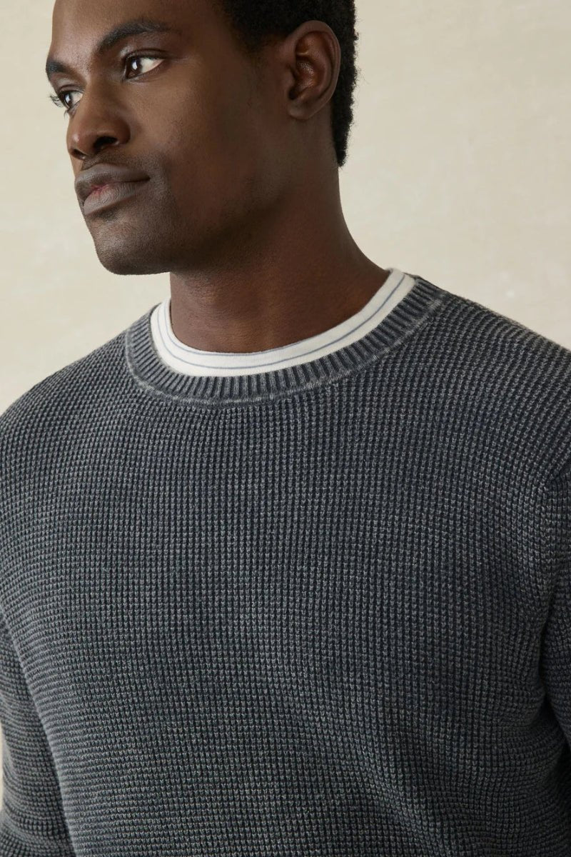 Man wearing a gray textured sweater against a beige background
