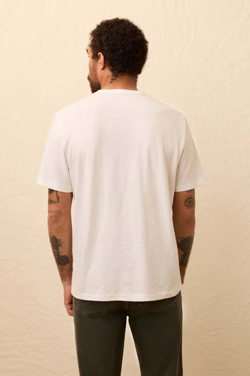 Person wearing a plain white t-shirt against a beige background