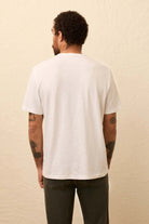 Person wearing a plain white t-shirt against a beige background