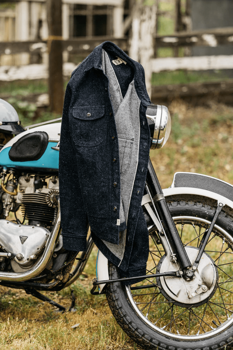 Denim jacket draped over a vintage motorcycle in an outdoor setting