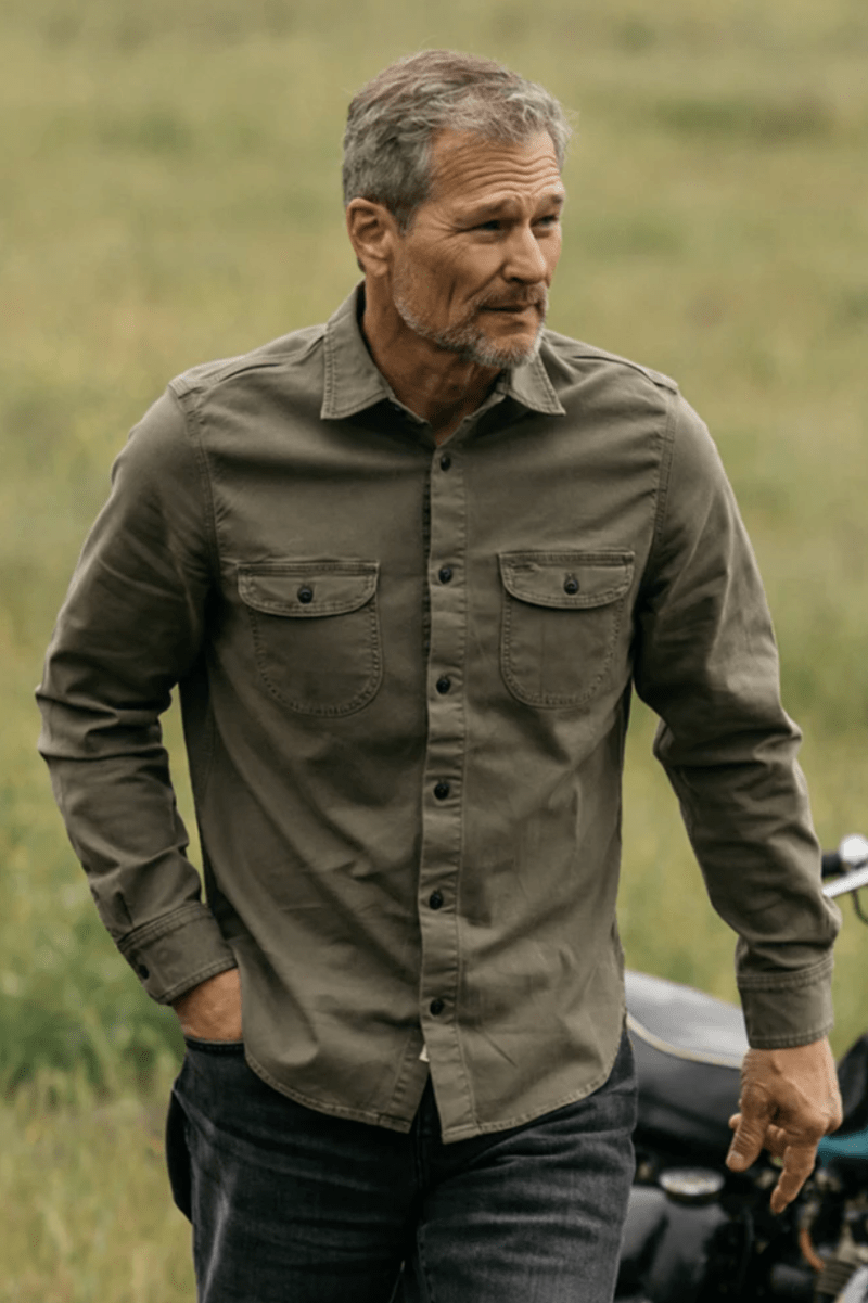 Man wearing a green shirt standing in a grassy field