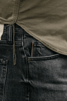 Close-up of dark jeans with a green shirt underneath