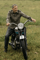 Man sitting on a motorcycle in a grassy field