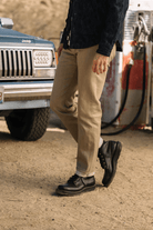Person wearing beige pants and black shoes standing next to a Jeep at a gas station.