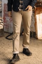Person wearing beige pants and black boots in a rustic setting