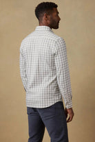 Man wearing a checkered shirt and dark pants against a beige background