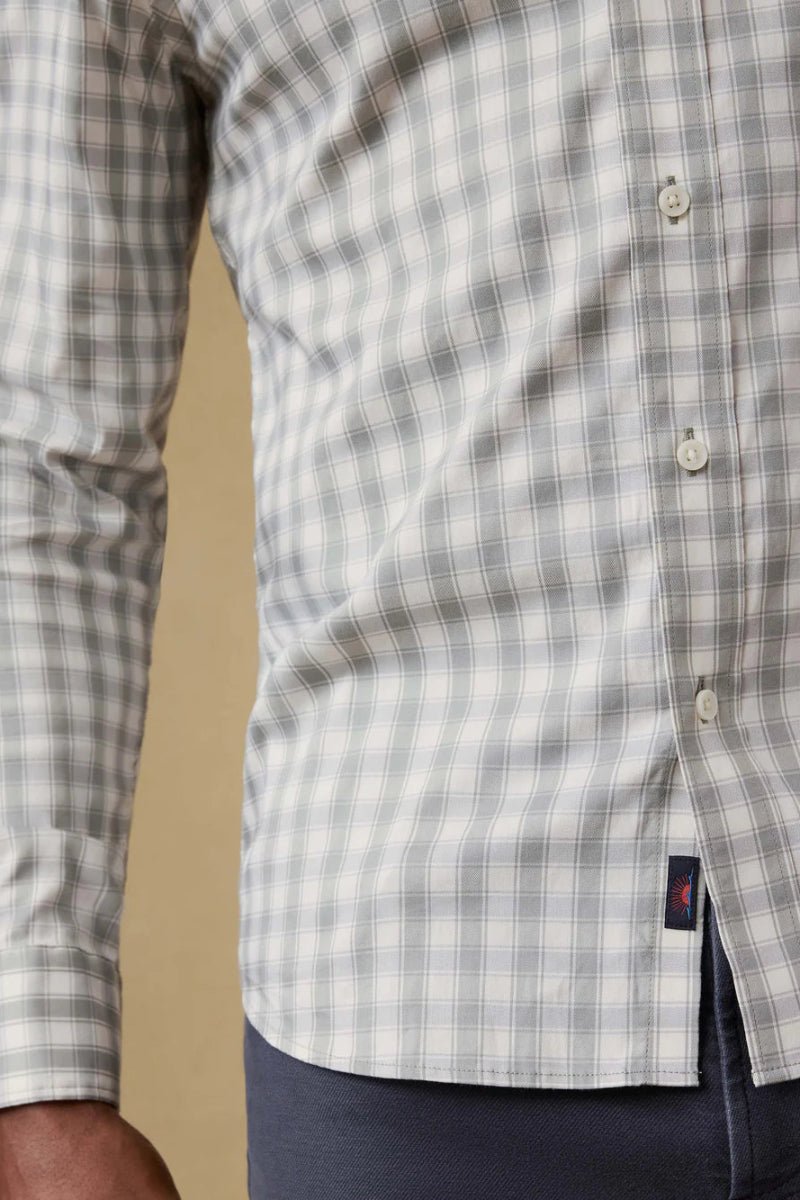 Close-up of a checkered shirt with a visible brand logo on a beige background