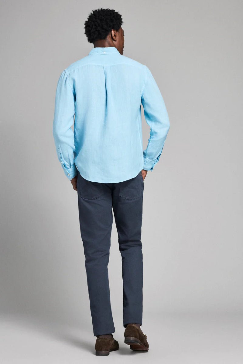 Person wearing a light blue shirt and dark pants on a plain background