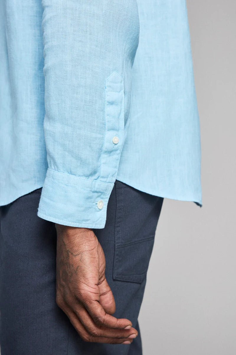 Light blue shirt with rolled-up sleeves and dark pants on a gray background