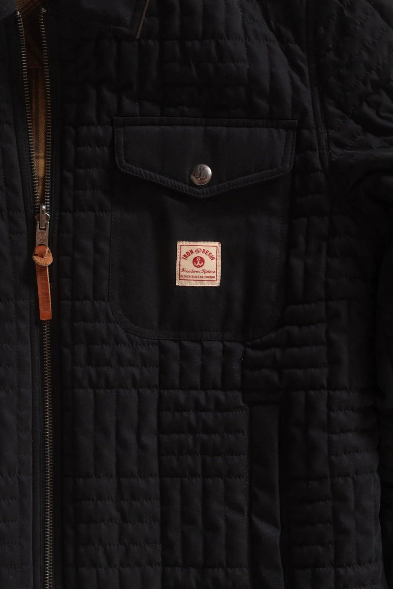 Close-up of a black quilted jacket with a brand logo on the chest pocket.