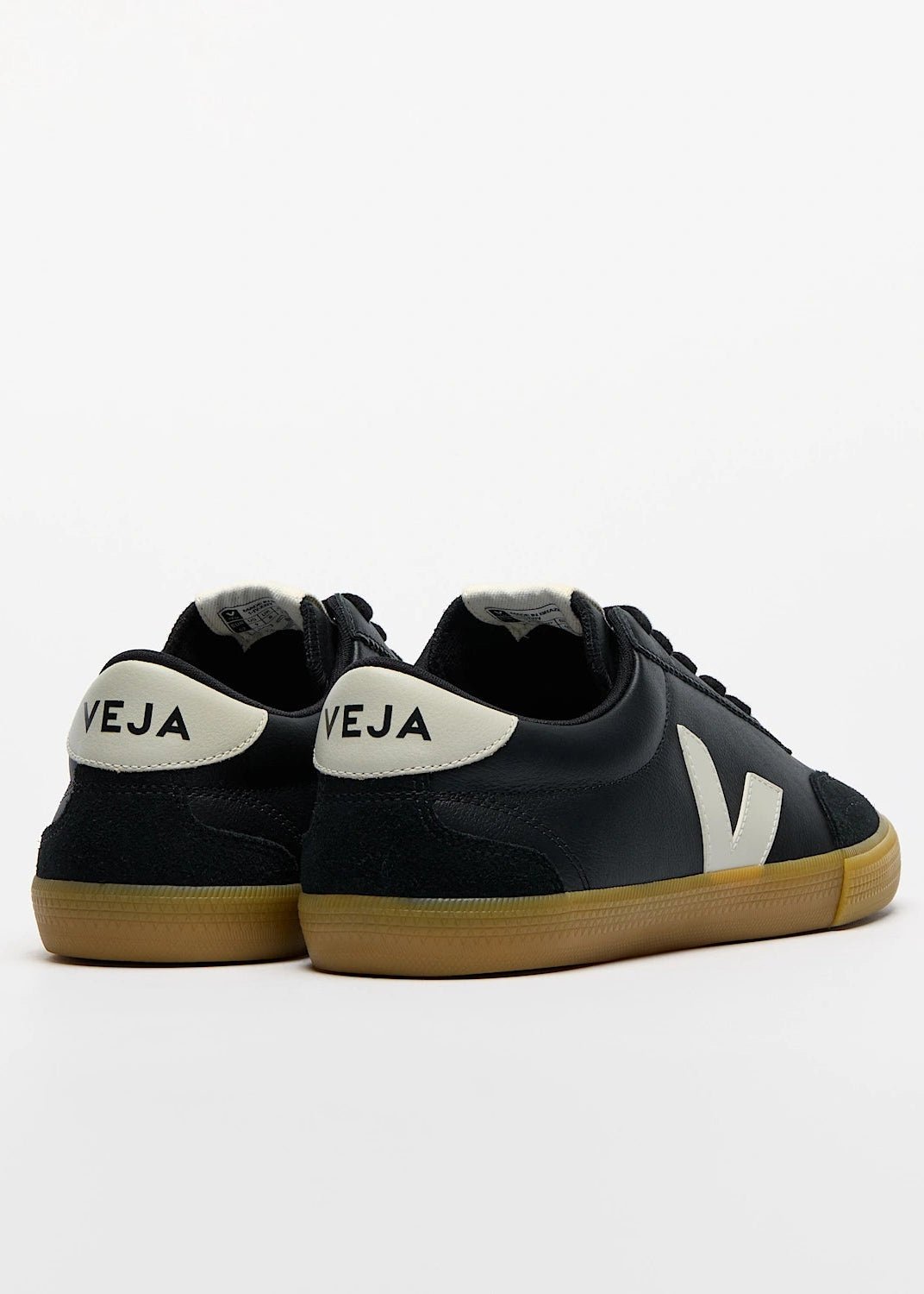 Black sneakers with white soles and 'Veja' branding on a light gray background