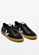 Black sneakers with yellow soles on a white background