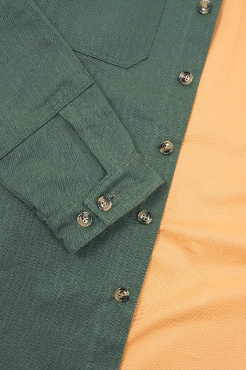 Close-up of a green jacket with buttons on a yellow background