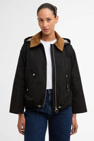 Person wearing a black jacket with a brown collar on a white background