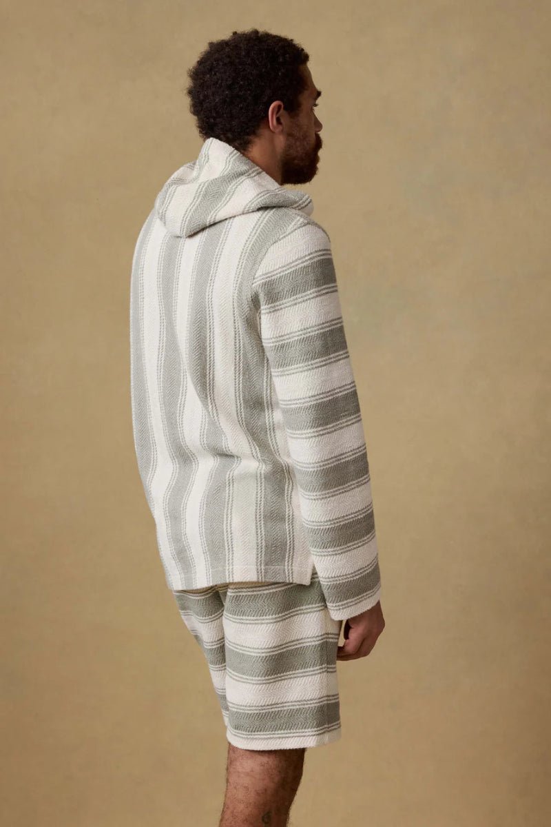 Man wearing a striped robe and shorts against a beige background