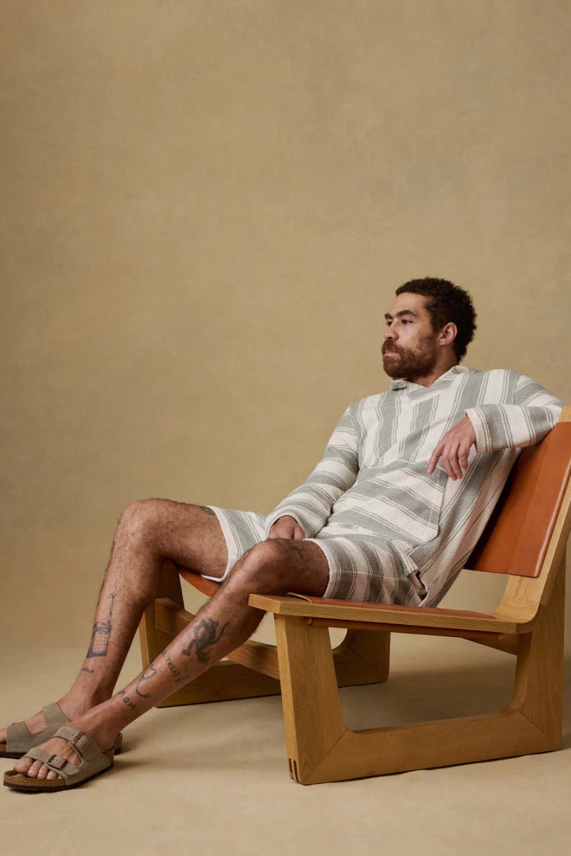 Man sitting on a wooden chair against a beige background