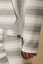 Close-up of a person wearing a patterned sweater with a visible brand logo on a beige background