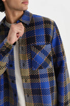 Person wearing a blue and brown plaid coat on a white background