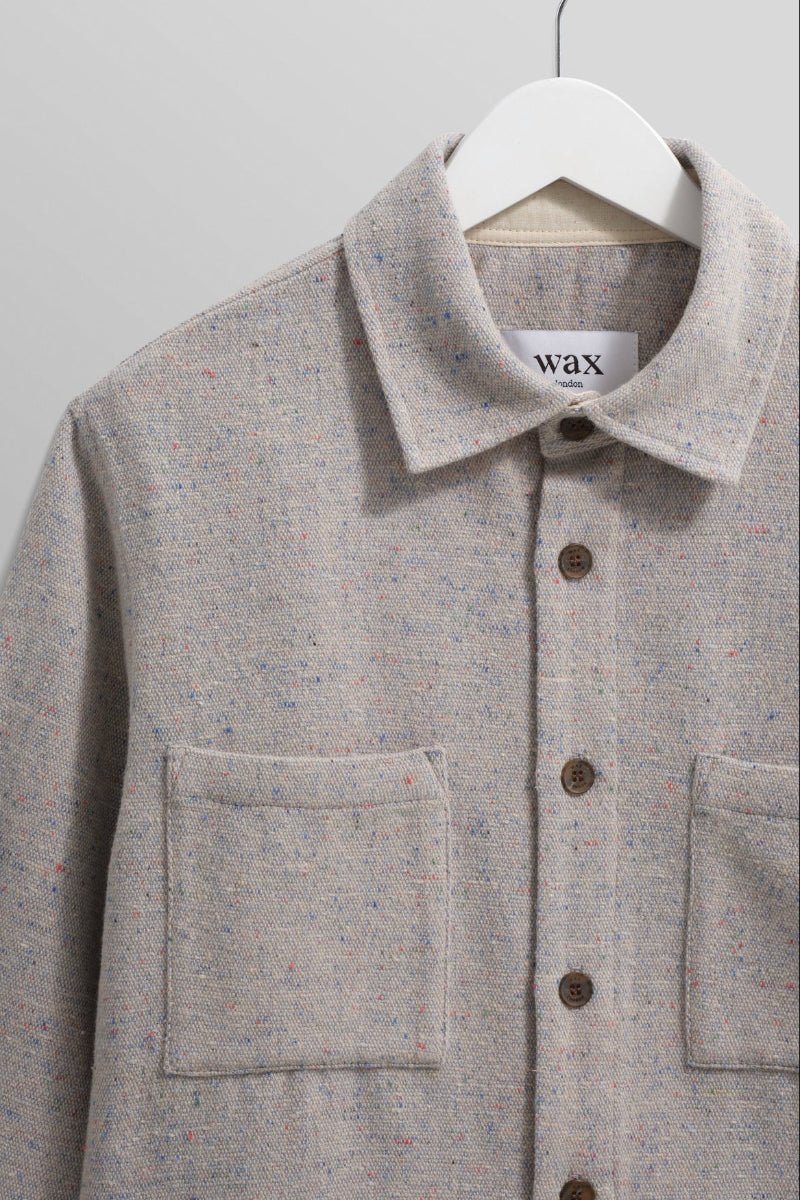 Gray textured shirt with button details on a hanger against a gray background