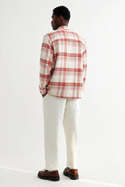 Person wearing a red and white plaid shirt with white pants on a white background
