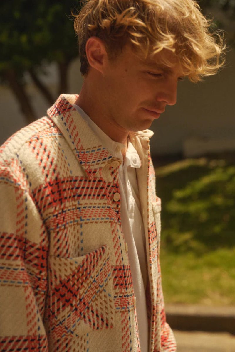 Man wearing a patterned shirt with a blurred outdoor background