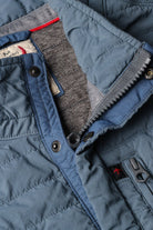 Close-up of a blue quilted jacket with visible stitching and buttons.